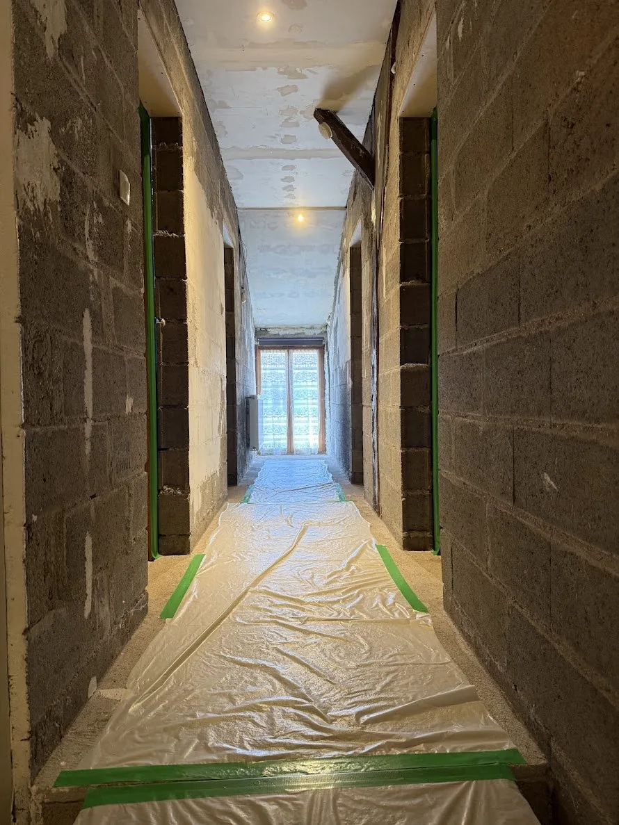 Couloir avant rénovation à Jarny, murs en parpaings bruts avec protection sol soignée