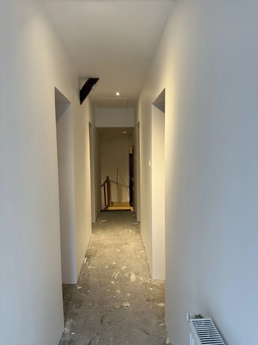 Couloir fini lumineux à Jarny, vue vers l'escalier en bois conservé