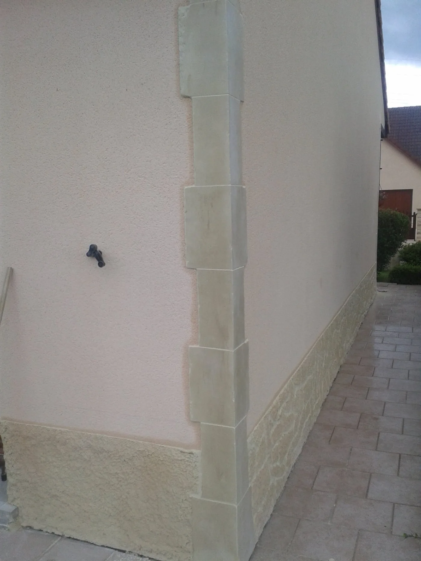 Angle de mur avec soubassement fausse pierre et pierres d'angle taillées verticales