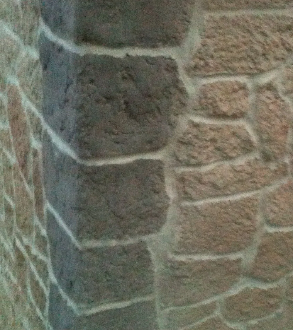 Gros plan sur la texture d'un angle de mur en enduit de chaux taillé à la main, aspect pierre naturelle