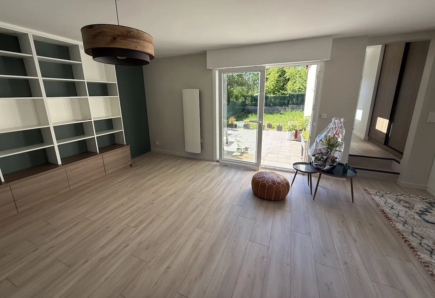 Séjour rénové avec parquet clair posé sur toute la surface, bibliothèque sur mesure et baie vitrée